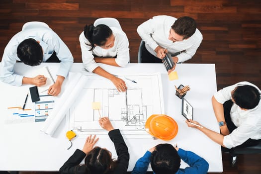 Top view banner of diverse group of civil engineer and client working together on architectural project, reviewing construction plan and building blueprint at meeting table. Prudent