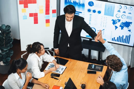 Wide top view of diverse group of business analyst team analyzing financial data report paper on meeting table. Chart and graph dashboard by business intelligence analysis. Meticulous