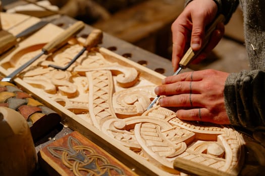 This image features a skilled artisan carpenter meticulously carving ornate and intricate patterns on a wooden surface, highlighting the artistry and precision in woodworking craftsmanship.