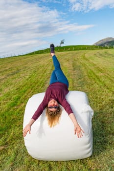 A stunning 40-year-old woman with confident poise, dressed in casual attire, posing gracefully on a densely packed hay stack in the midst of a tranquil and picturesque field.