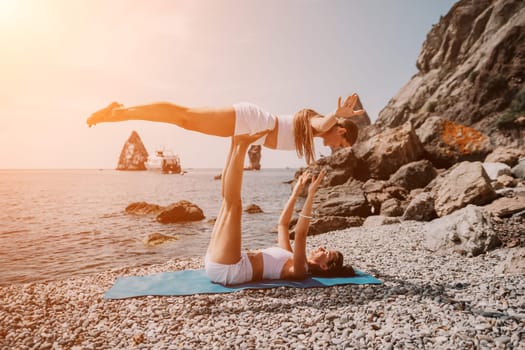 Woman sea yoga. Back view of free calm happy satisfied woman with long hair standing on top rock with yoga position against of sky by the sea. Healthy lifestyle outdoors in nature, fitness concept.