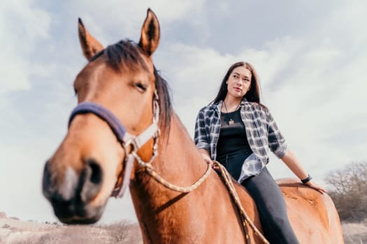 Cute happy young woman with horse. Rider female drives her horse in nature on evening sunset light background. Concept of outdoor riding, sports and recreation.