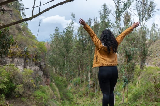 copyspace of young Latin American woman on top of a mountain with open arms enjoying the freedom and relaxation of the place. High quality photo