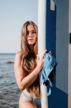 Close up shot of beautiful young caucasian woman with black hair and freckles looking at camera and smiling. Cute woman portrait in a pink bikini posing on a volcanic rock high above the sea