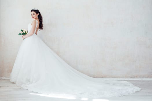 Princess Bride in a wedding dress with a train standing in a room of vintage