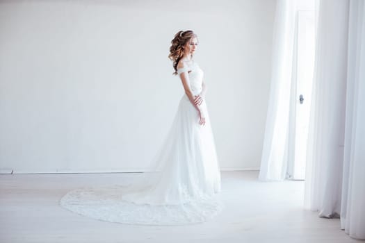bride in wedding dress in a white room before wedding