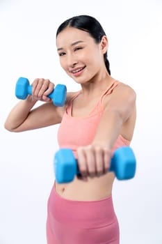 Vigorous energetic woman doing dumbbell weight lifting exercise on isolated background. Young athletic asian woman strength and endurance training session as body workout routine.