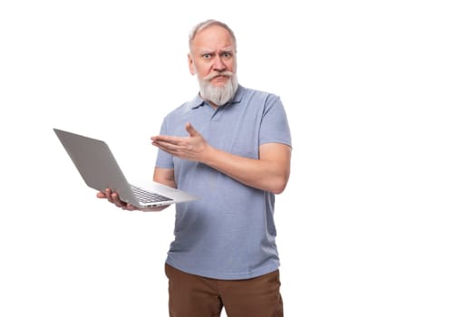 a cute grandfather with a gray beard and mustache is holding a laptop for work. e-business concept.