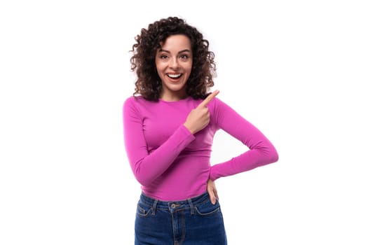 pretty smiling young curly brunette woman dressed in a purple turtleneck points with her hands at the advertisement.