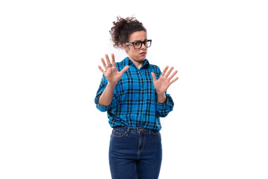 cute young pretty woman with curled hair gathered in a bun shows her disagreement on a white background with copy space.