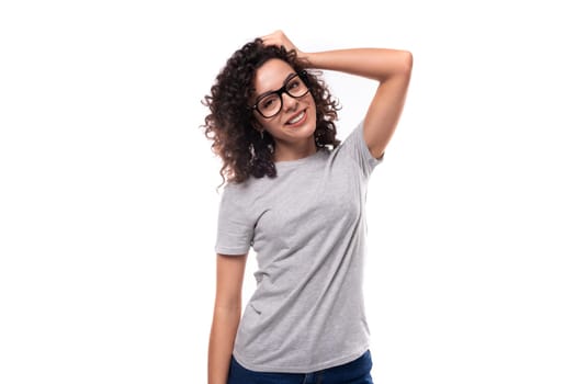 adorable slim curly brunette promoter woman with glasses dressed in gray basic t-shirt with logo print mockup.