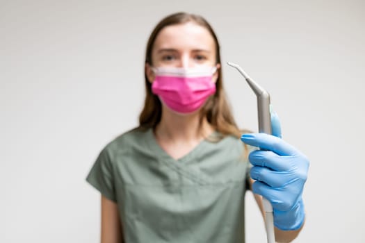 Dentist in face mask holding air and water syringe in dentist hand in rubber gloves.