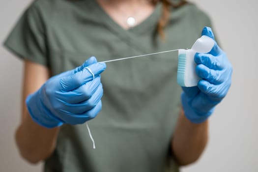 Oral floss manipulated by a dental practitioner wearing rubber gloves