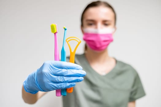 Dentist in face mask holding toothbrushes in her hand.