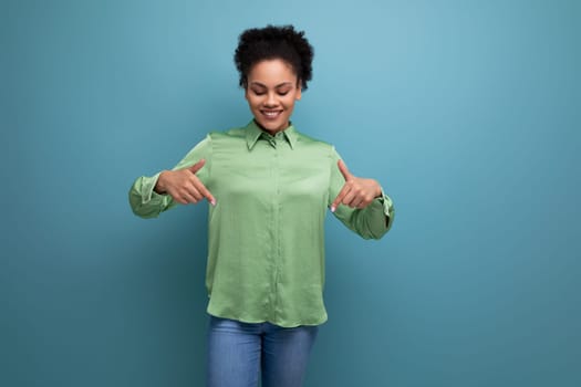 young cheerful latin business lady in green blouse showing hands down on studio background with copy space.
