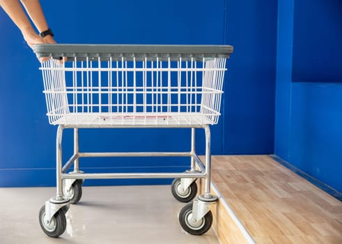 Laundry and housework. Woman hands holding empty new white trolley cart, metal cart parked use for laundry at convenience store for support customer, Laundromat convenience store concept