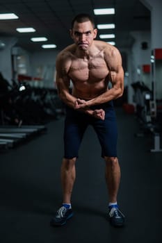 Shirtless man with sculpted body posing in the gym