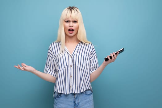pretty european 20s woman in a striped shirt with a mobile phone in her hands on a studio background.