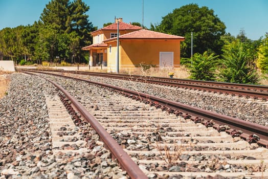 travel concept image with train tracks in the foreground and an empty train station out of focus in the background