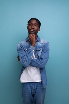 portrait of a shy young african man with dreadlocks in a denim jacket posing thoughtfully.