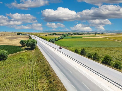 Aerial view of cars and transport trucks on Highway with fields on both sides