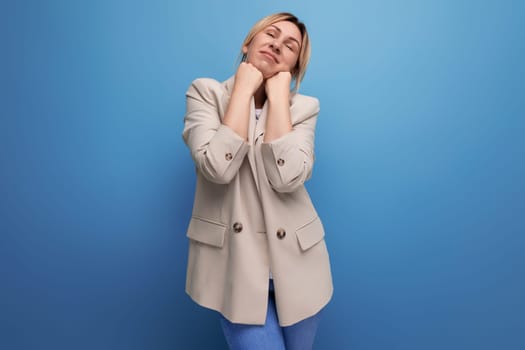 dreaming 30 year old woman in a jacket with blond hair on a studio background with copy space.