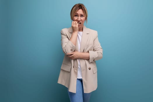 pensive serious blond business young woman in jacket on studio background.