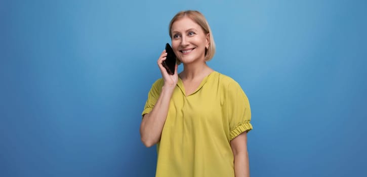 blond middle aged woman chatting on the phone in studio background.