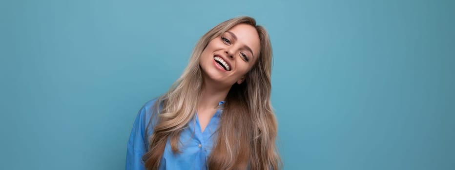 horizontal wide photo of adorable blonde young woman on blue background with empty space.
