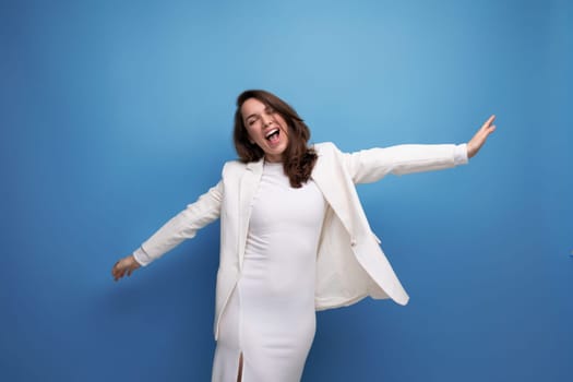 cheerful healthy young lady with dark hair below her shoulders is flirting on a studio background with copy space.