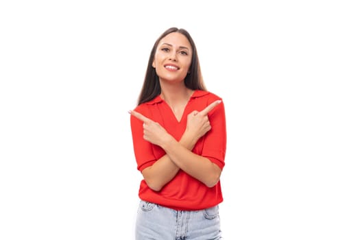 portrait of a pretty brunette woman with straight hair in a red t-shirt and jeans pointing with her hands at the advertising space.