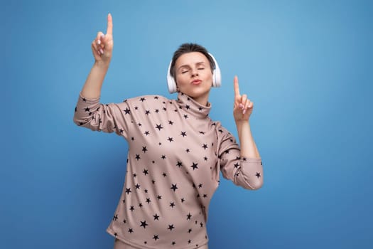 pretty cute young european business woman with short dark hair enjoying music in wireless bluetooth headphones.