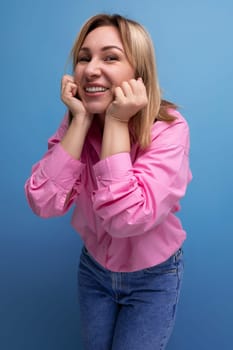 young pretty blond european office worker woman with flowing hair in a pink blouse smiles sweetly.