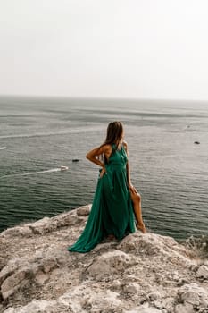 Woman sea trevel green dress. Side view a happy woman with long hair in a long mint dress posing on a beach with calm sea bokeh lights on sunny day. Girl on the nature on blue sky background