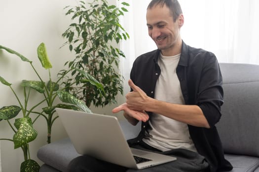 Young man showing gesture in sign language using laptop, make video call.