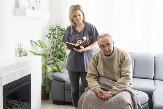 Caring nurse talks to old patient holds his hand sit in living room at homecare visit provide psychological support listen complains showing empathy encouraging. Geriatrics medicine caregiving concept.