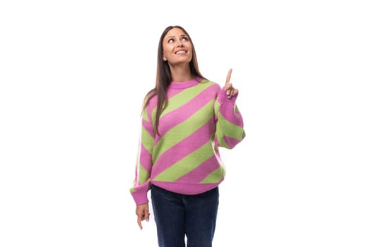 stylish cheerful young brunette woman in a striped pink blouse points fingers at the space for advertising on a white background with copy space.