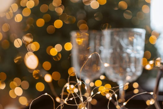 Champagne glasses, New Year decor. New Year's festive setting, family holidays.Two glasses of champagne are on the table against the background of New Year's decorated tree