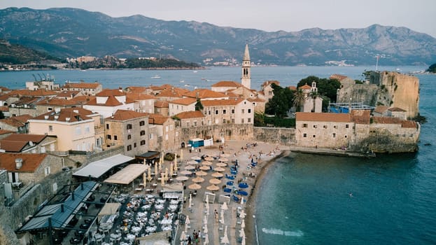 Beach near the stone fortress walls of the old town of Budva on the seashore. Montenegro. Drone. High quality photo