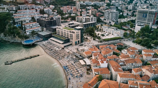 Beach with sun umbrellas on the seashore between the old and new parts of Budva. Montenegro. Drone. High quality photo