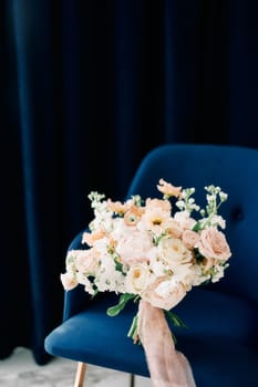 Colorful bridal bouquet stands on a blue soft chair. High quality photo