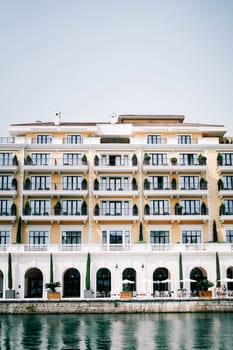Chairs and tables stand on the terrace by the sea in front of the Regent Hotel. Porto, Montenegro. High quality photo