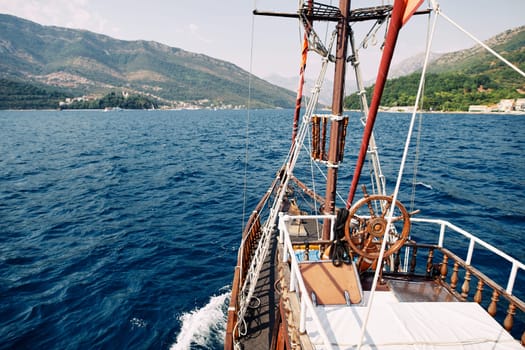 Deck of a wooden ship with a steering wheel sailing on the sea. High quality photo