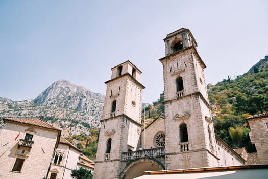 Bell towers of the Cathedral of St. Tryphon among ancient houses at the foot of the mountains. Kotor, Montenegro. High quality photo
