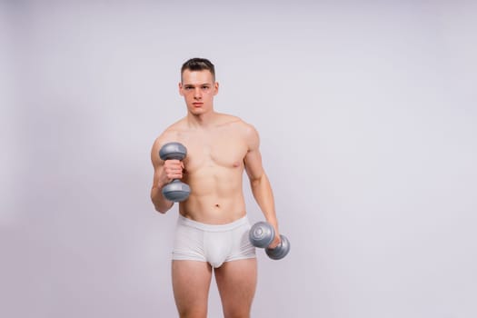 Man with pumped-up body with dumbbells in his hands white panties exercise