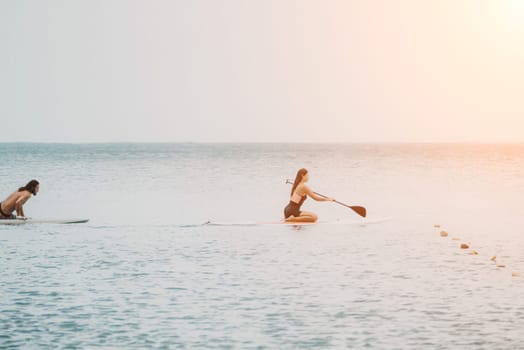 Sea woman and man on sup. Silhouette of happy young woman and man, surfing on SUP board, confident paddling through water surface. Idyllic sunset. Active lifestyle at sea or river