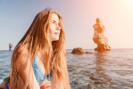 Close up shot of happy young caucasian woman looking at camera and smiling. Cute woman portrait in bikini posing on a volcanic rock high above the sea