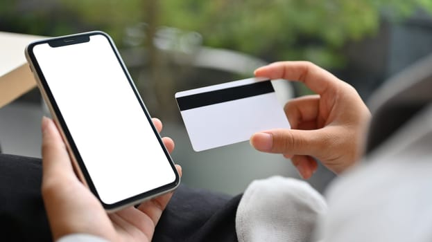 Woman holding credit card and using mobile phone making payment or ordering via the internet.