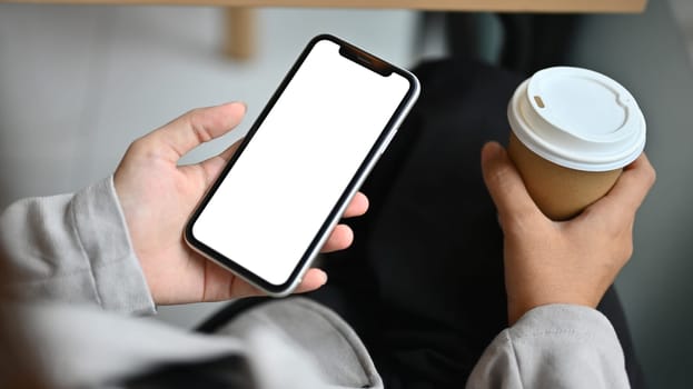 Closeup businesswoman with paper cup in hand using mobile phone at cafe.