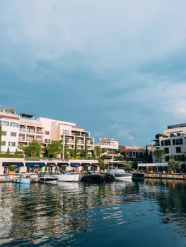 Motor yachts are moored along the shore with colorful hotels and expensive shops. Porto, Montenegro. High quality photo